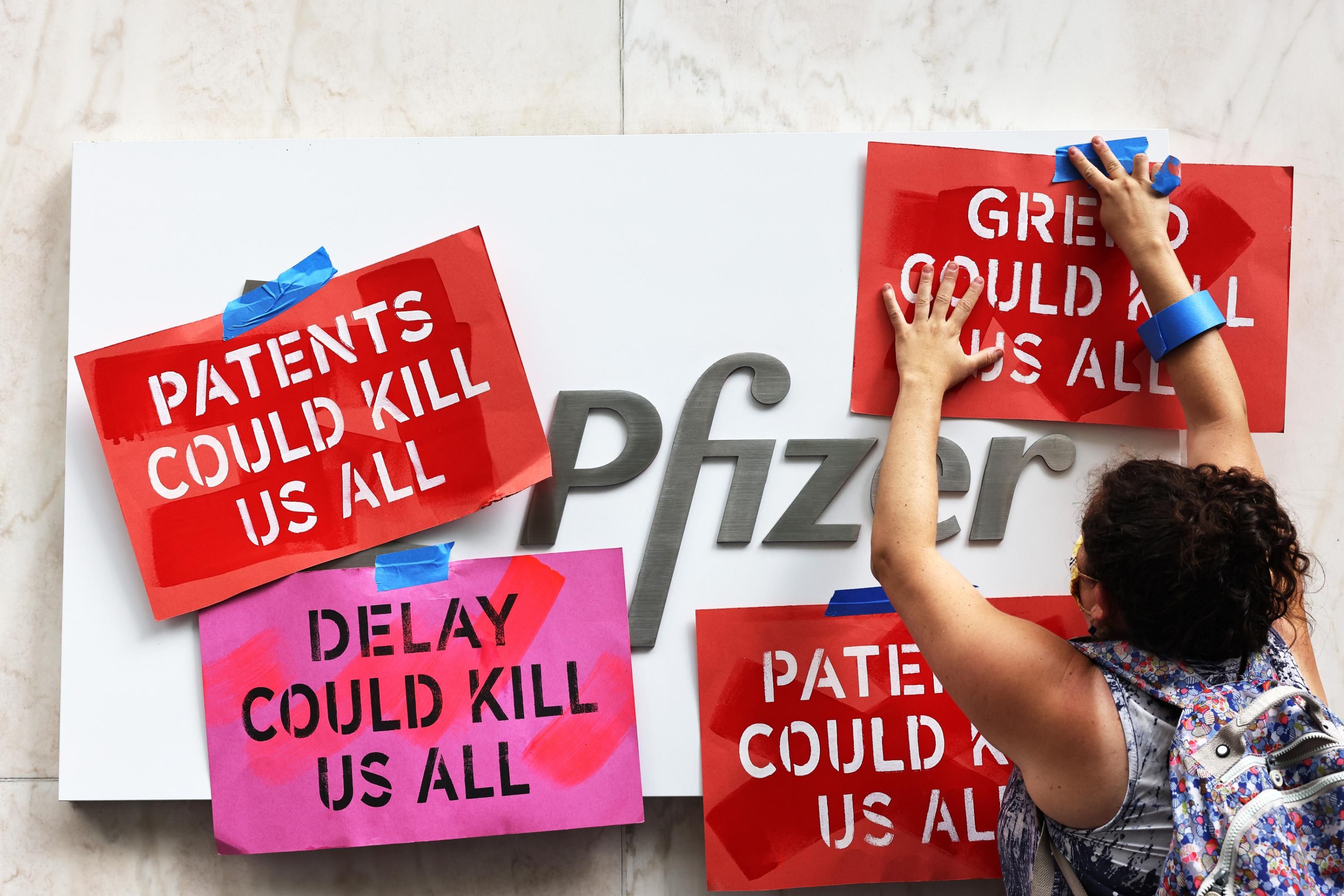 A demonstrator tapes signs to Pfizer headquarters
