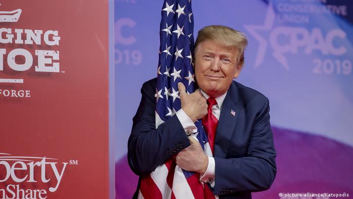 Präsident Trump umarmt die US Flagge (picture-alliance/Katopodis )