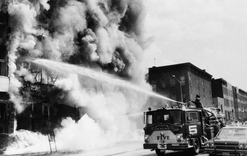 On this date in 1977: Firefighters fight a blaze above a row of looted stores in Brooklyn the day after a power failure that swept across New York City and led to widespread chaos and looting. 