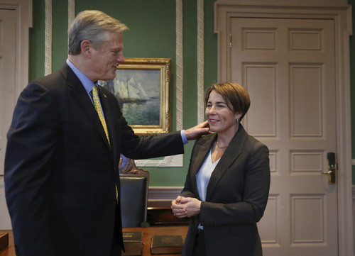 Massachusetts Gov. Charlie Baker presents traditional symbols, including challenge coin, to Gov-elect Maura Healey during a ritual exchange, Wednesday, Jan. 4, 2023, at the State House in Boston. (Nancy Lane/The Boston Herald via AP, Pool)