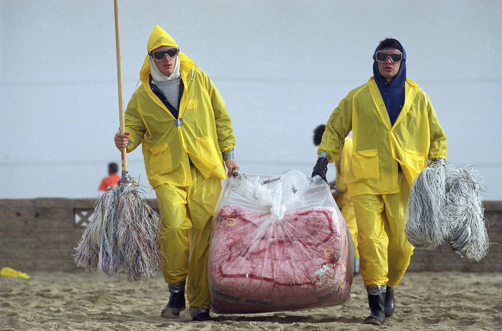 On this date in 1990: Workers carry absorbent pom-poms and large plastic bag with mini-booms as they head for the surf at Bolsa Chica State Beach near Huntington Beach, Calif.. Waves of gooey brown foam and sludge came ashore after an oil spill that sent more than 416,000 gallons of oil into the ocean. 
