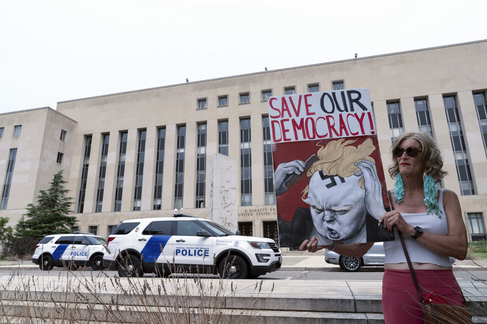 A woman holds a sign outside the Federal District Court in Washington on Tuesday, where a grand jury indicted former President Donald Trump in the probe led by special counsel Jack Smith. 