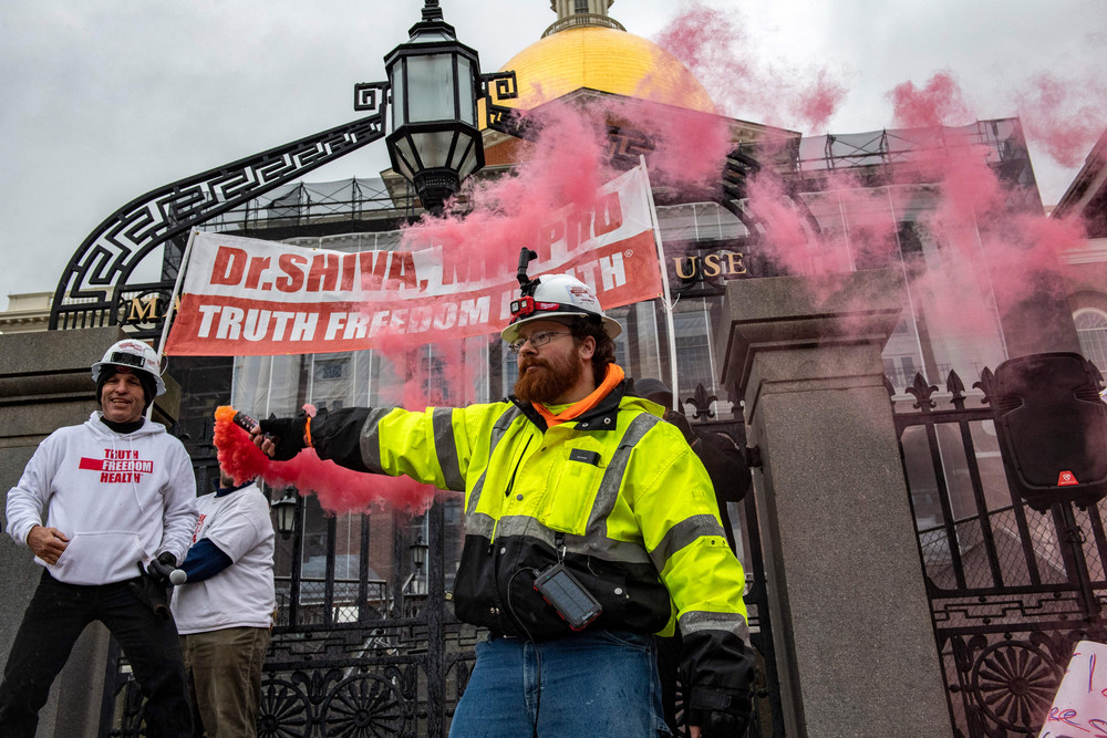 A man releases smoke from a flare during a "truth, freedom rally" as hundreds of people protest against vaccines, vaccine mandates and vaccine passports at the State House in Boston, Massachusetts on Jan. 5, 2022. 