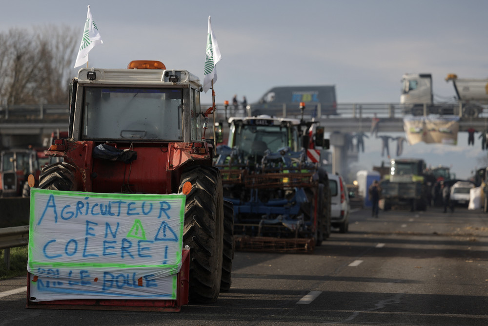 A tractor with a banner that reads "angry farmer" blocks a section of the A64 highway in France.