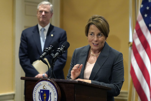 Massachusetts Democratic Attorney General Maura Healey, right, speaks to reporters as Republican Mass. Gov. Charlie Baker, behind, looks on during a news conference, Wednesday, Nov. 9, 2022, at the Statehouse, in Boston. Hours after she was elected governor of the state Healey met with Baker at the Statehouse to discuss the upcoming transfer of power. (AP Photo/Steven Senne)