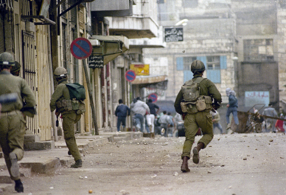 On this date in 1987: Two Israeli soldiers run towards a group of Palestinian youth, background, who had been hurling rocks and bottles at them in Nablus — a city in the West Bank — during demonstrations throughout the city and other parts of the region. The demonstrations, termed the first Palestinian Intifada, began after an Israeli truck driver struck a car and killed four Palestinian civilians on Dec. 9, 1987, and lasted through the Madrid
 Conference of 1991. 