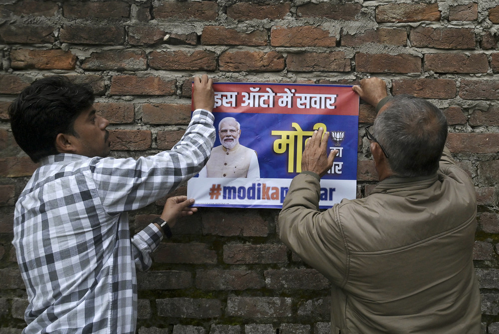 Bharatiya Janata Party activists paste a poster with the image of BJP leader and Indian Prime Minister Narendra Modi on a wall near a polling station during the first phase of voting of India's general elections in Jammu on April 19. 