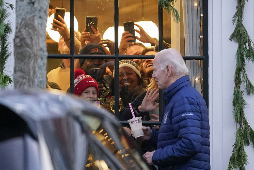People react as President Joe Biden walks by as he visits local shops with family in Nantucket, Mass., Saturday, Nov. 25, 2023. (AP Photo/Stephanie Scarbrough)