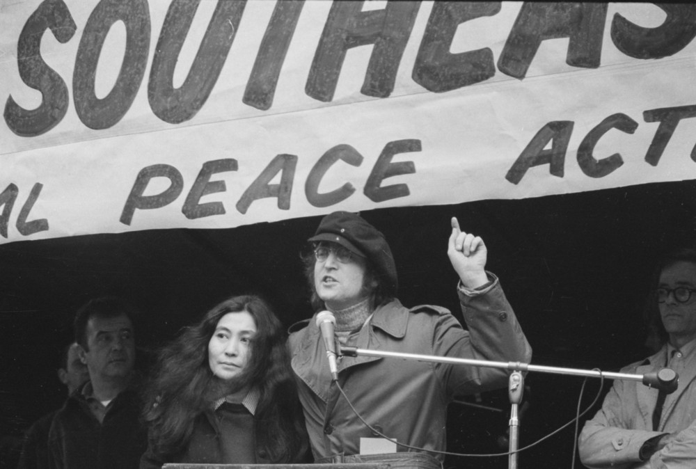On this date in 1972: John Lennon gestures as he speaks at a peace rally in New York's Bryant Park. Standing beside him is his wife, Yoko Ono.  The rally and march of some 30,000 people in New York City was part of a nationwide day of protests and demonstrations against U.S. involvement in the Vietnam War. 