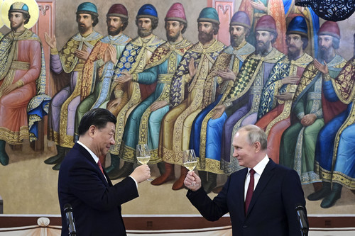Chinese President Xi Jinping and Russian President Vladimir Putin hold wine glasses aloft in a toast during a dinner at The Palace of the Facets, a building in the Kremlin.