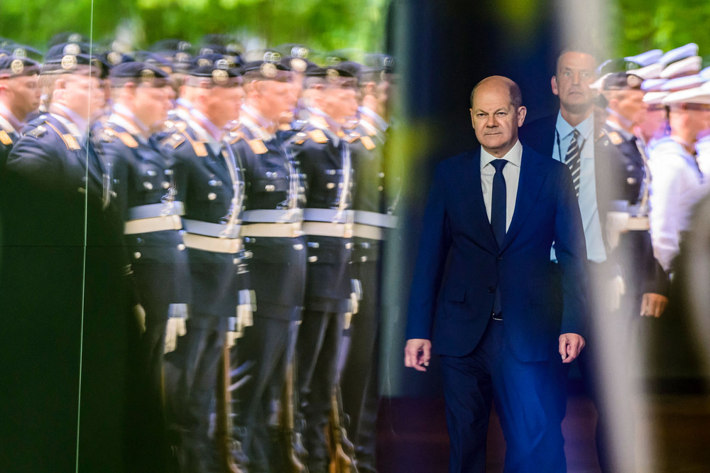 German Chancellor Olaf Scholz walks out of the chancellery to greet the President of Cyprus, as a German honor guard is reflected in the glass facade of the building in Berlin today. 