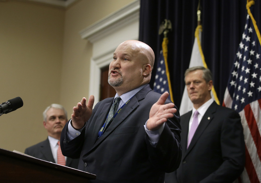 Massachusetts Commissioner of Elementary and Secondary Education Jeffrey Riley, center, faces reporters as Mass. Gov. Charlie Baker, right, looks on during a news conference, Wednesday, Jan. 23, 2019 at the Statehouse, in Boston. Baker unveiled his state budget proposal during the news conference Wednesday. (AP Photo/Steven Senne)