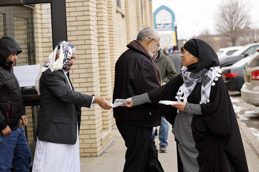 Samra'a Luqman hands out fliers outside of the American Moslem Society Mosque in Dearborn Heights, Mich. to ask voters not to vote for President Joe Biden.