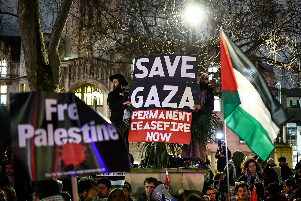 Pro-Palestinian demonstrators wave Palestinian flags and hold placards as they protest in Parliament Square in London.