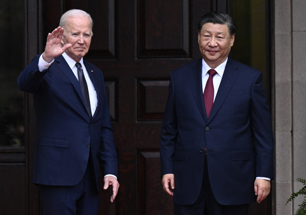 Joe Biden waves as he stands beside Xi Jinping. 