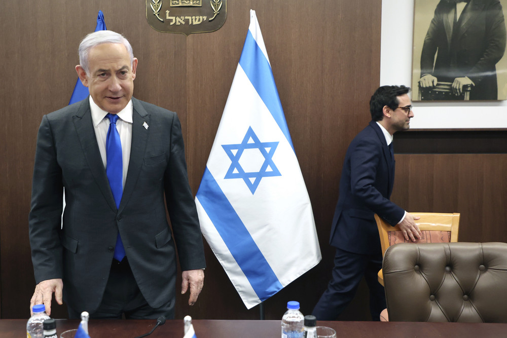 Benjamin Netanyahu stands at a conference table as Stephane Sejourne walks behind him.