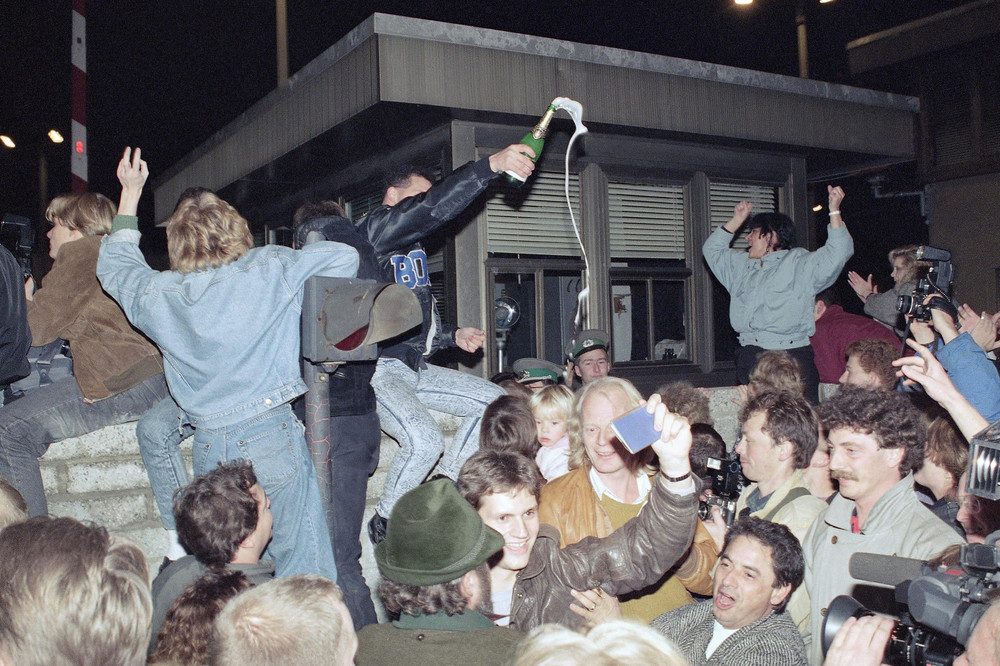 On this date in 1989: The Berlin Wall falls and borders open between East and West Berlin. Pictured are East and West Berliners celebrating in front of a control station on East Berlin territory. 