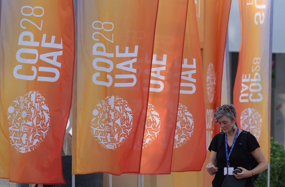 A woman walks past banners at the UNFCCC COP28 Climate Conference in Dubai. 