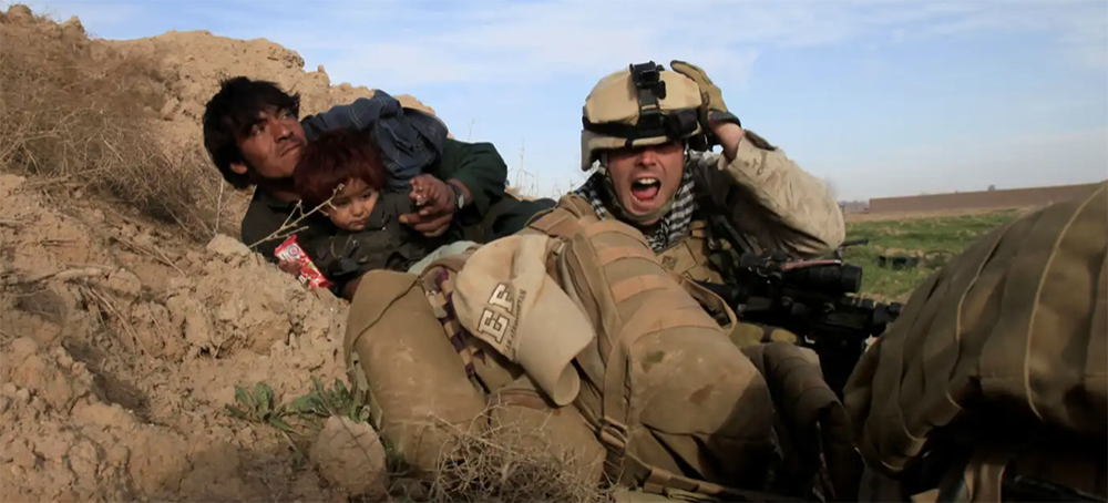A US Marine shouts as he tries to protect an Afghan man and his child after Taliban fighters opened fire in the Helmand Province town of Marjah in Afghanistan in 2010. (photo: Reuters)