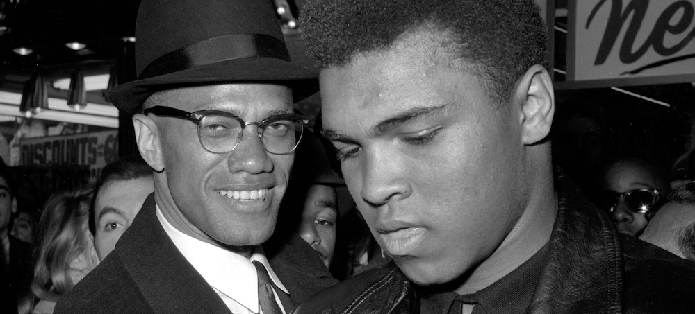 Muhammad Ali, world heavyweight boxing champion, stands with Malcolm X outside the Trans-Lux Newsreel Theater in New York in 1964. (photo: AP)