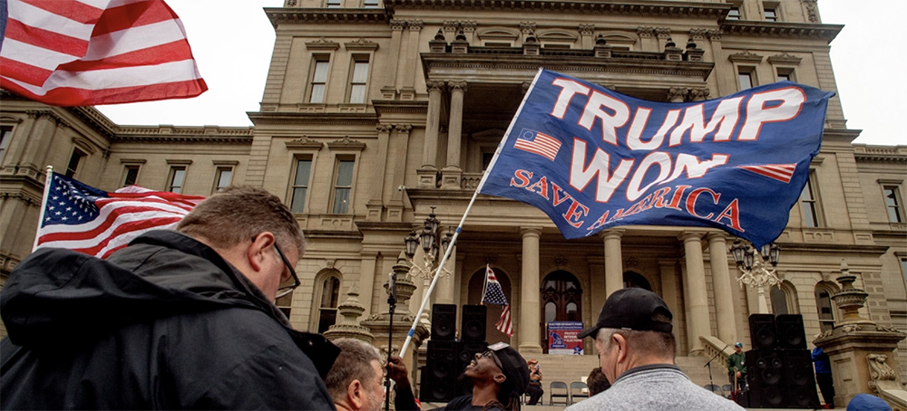 A protester waves a Trump flag during rally at the Michigan State Capitol, on October 12th, 2021, in Lansing, Michigan. The event, organized by a group called Election Integrity Fund and Force, is demanding a 'forensic audit' of the state's 2020 presidential election results. (photo: Jake May/The Flint Journal/AP)