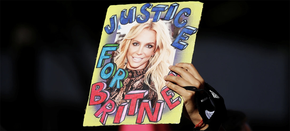 A supporter holds up a picture of Britney Spears with the words 'Justice for Britney' at celebrations for the termination of her conservatorship outside the Stanley Mosk Courthouse in Los Angeles on Friday. (photo: Mike Blake/Reuters)