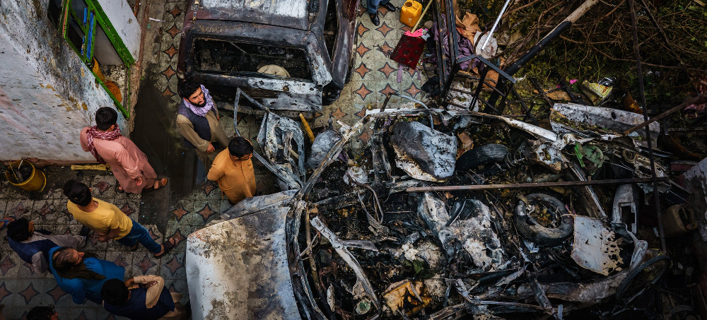 Relatives and neighbors of the Ahmadi family gather around the incinerated husk of their vehicle, targeted and hit by an American drone strike, in Kabul, Afghanistan, on Aug. 30, 2021. (photo: Marcus Yam/Getty)