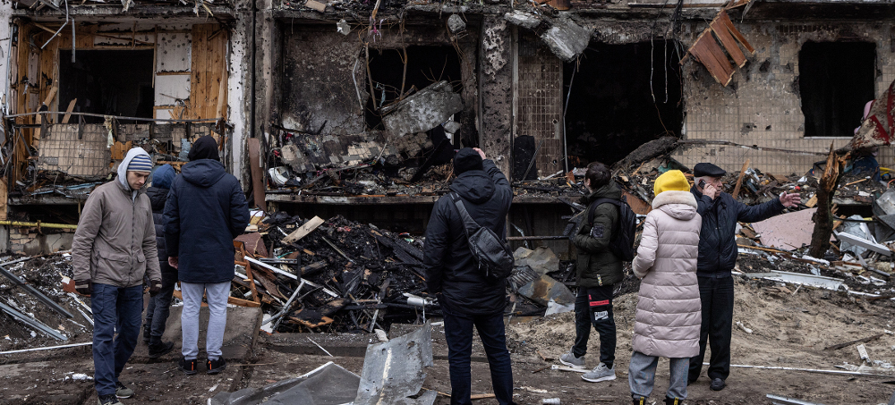 People look at the exterior of a damaged residential block hit by an early morning missile strike on February 25, 2022, in Kyiv, Ukraine. (photo: Chris McGrath/Getty)
