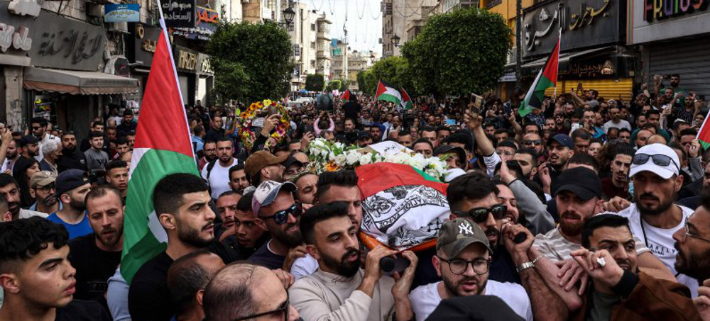 Palestinians carry the flag-draped body of veteran Al Jazeera journalist Shireen Abu Akleh as they walk toward the offices of the news channel in the West Bank city of Ramallah, on May 11, 2022. (photo: Ronaldo Schemidt/Getty)