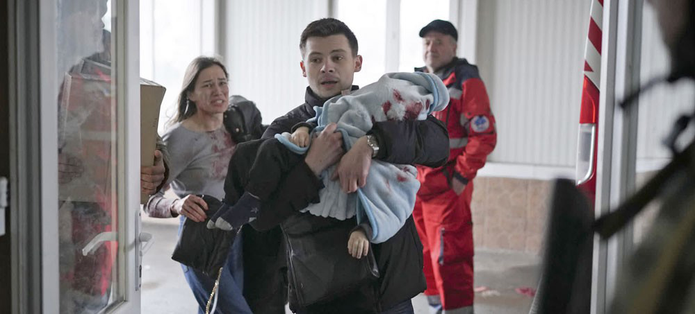 Mariupol, Ukraine, March 4, 2022: A man and woman rush a child wounded by Russian shelling to an emergency room. The child did not survive. (photo: Evgeniy Maloletka/AP)