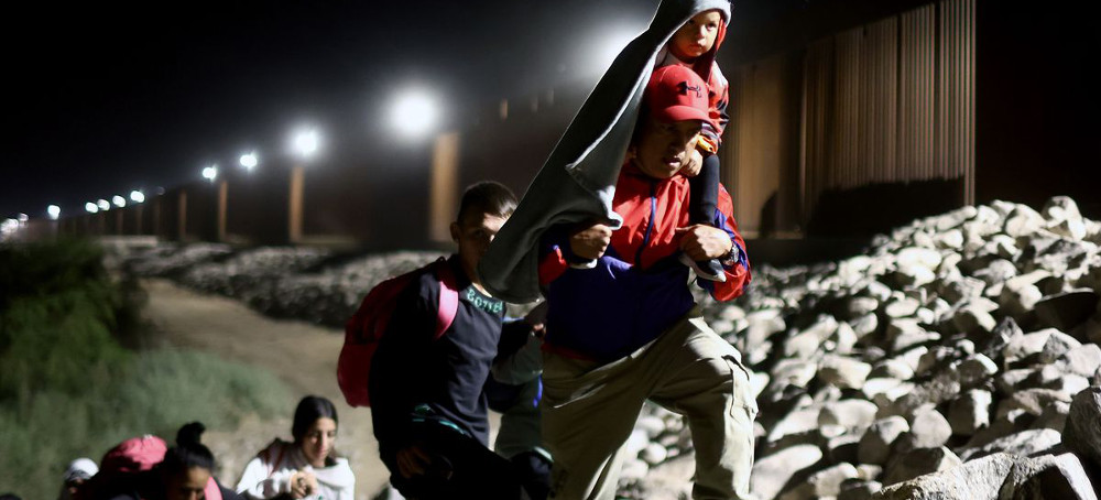 Immigrants seeking asylum in the United States walk along the border fence on their way to be processed by U.S. Border Patrol agents in the early morning hours after crossing into Arizona from Mexico on May 11, 2023, in Yuma, Arizona. (photo: Mario Tama/AFP)