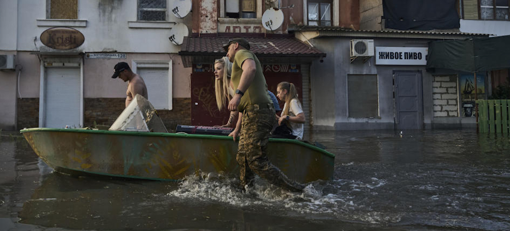 Rescue workers help residents evacuate from a flooded neighborhood in Ukraine on Tuesday. (photo: Libkos/AP)