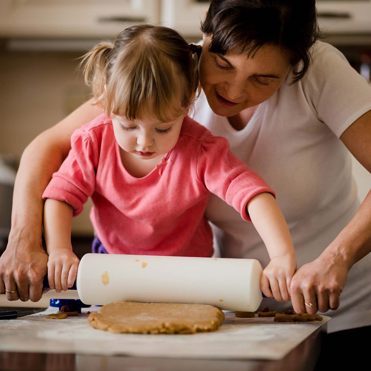 Mother and daughter rolling out dough