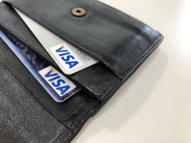 Munich, Germany Bavaria - May 22, 2021: VISA credit and debit cards in a black leather wallet with a white table surface background.