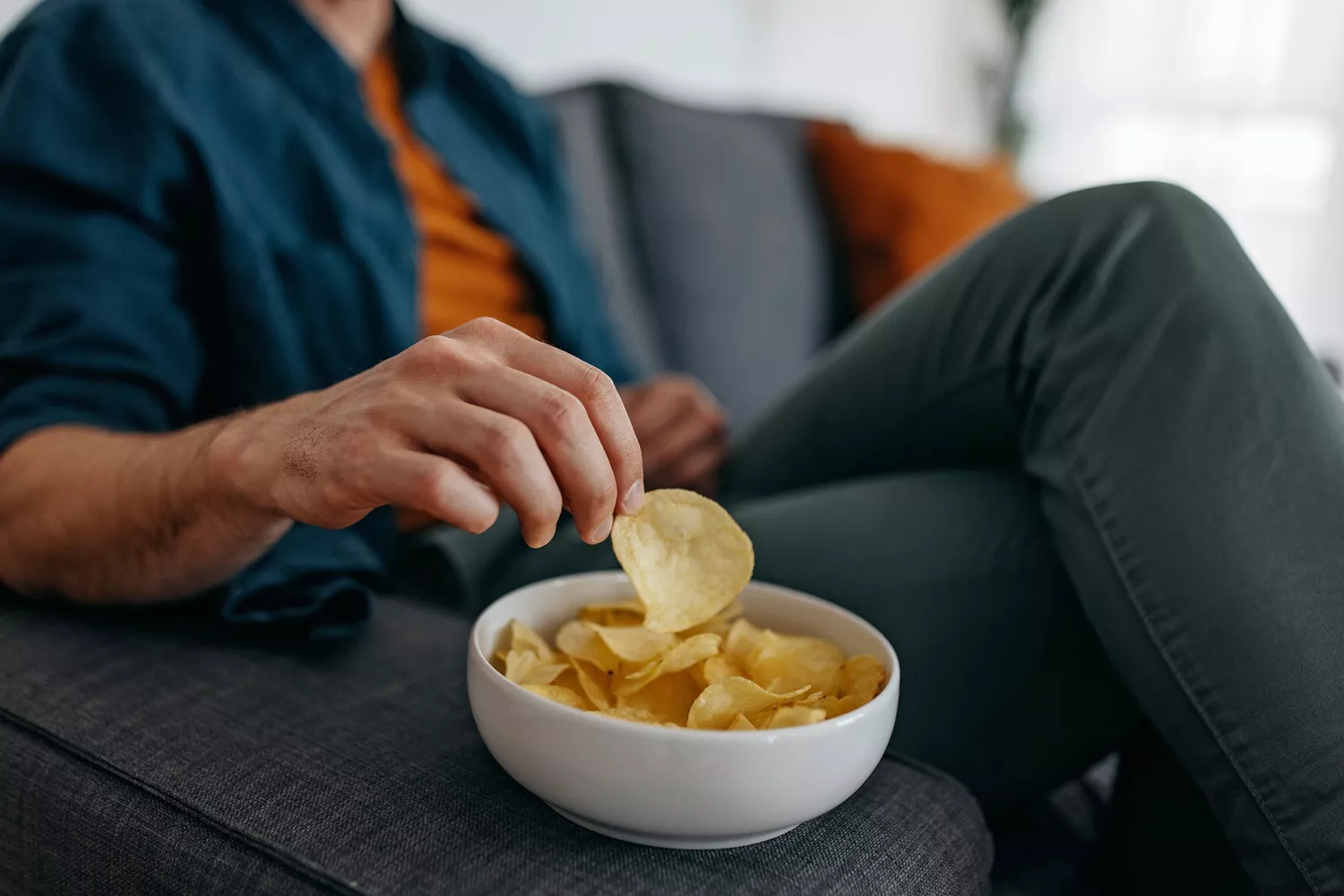 A person eating potato chips at home