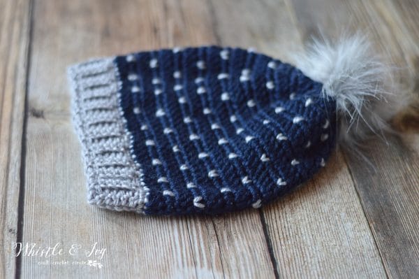 crochet navy blue hat with gray hearts knit stitch and gray fur pom-pom 